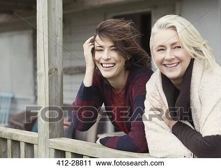 Stock Image - Portrait smiling mother and daughter on windy porch. Fotosearch