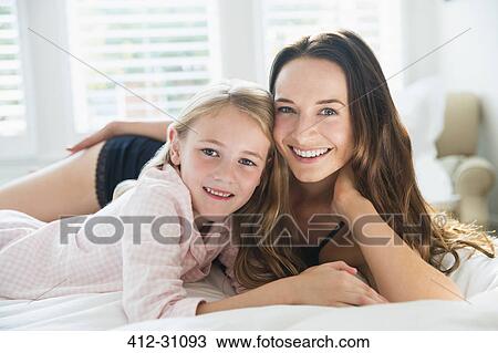Portrait smiling mother and daughter laying on bed View Large Photo Image Stock Image - Portrait smiling mother and daughter laying on bed. Fotosearch