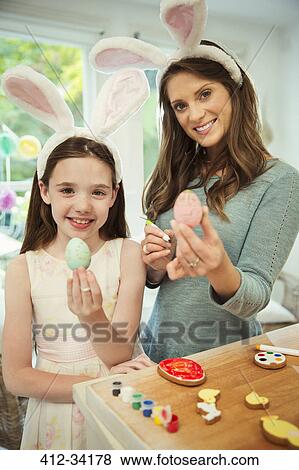 Stock Photo - Portrait smiling mother and daughter wearing costume rabbit ears showing decorated Easter eggs. Fotosearch