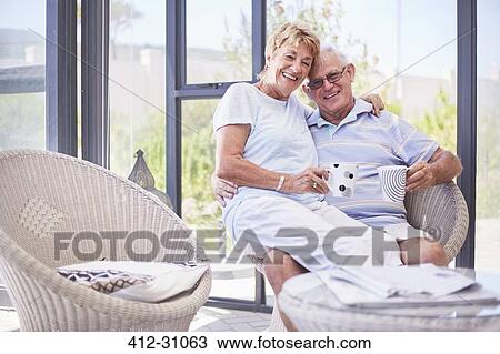 Stock Image - Portrait smiling senior couple drinking coffee on sun porch. Fotosearch