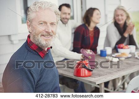 Stock Image - Portrait smiling senior man enjoying breakfast with family on patio. Fotosearch