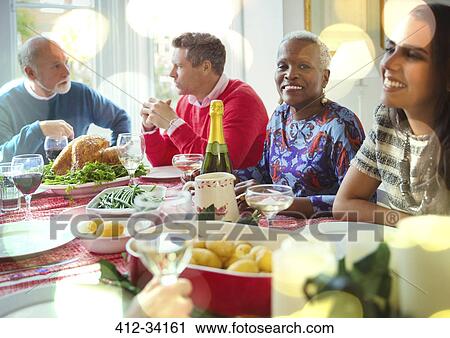 Stock Image - Portrait smiling senior woman enjoying Christmas dinner with family at table. Fotosearch