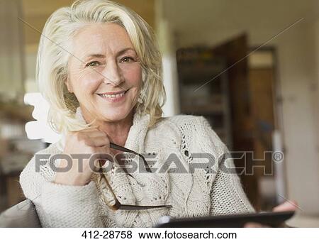 Stock Photo - Portrait smiling senior woman in sweater holding digital tablet. Fotosearch