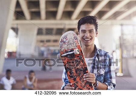 Portrait smiling teenage boy holding skateboard at skate park View Large Photo Image Stock Photography - Portrait smiling teenage boy holding skateboard at skate park. Fotosearch
