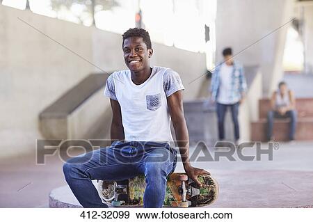 Portrait smiling teenage boy sitting on skateboard at skate park View Large Photo Image Stock Photo - Portrait smiling teenage boy sitting on skateboard at skate park. Fotosearch