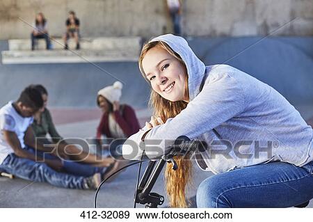 Portrait smiling teenage girl leaning on BMX bicycle at skate park View Large Photo Image Stock Photo - Portrait smiling teenage girl leaning on BMX bicycle at skate park. Fotosearch