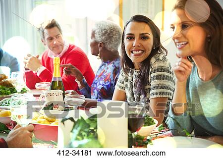 Stock Image - Portrait smiling woman enjoying Christmas dinner at table. Fotosearch