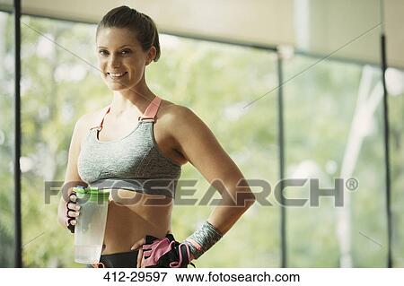 Portrait smiling woman holding water bottle at gym View Large Photo Image Stock Photo - Portrait smiling woman holding water bottle at gym. Fotosearch
