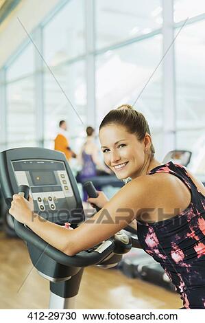 Portrait smiling woman on exercise bike at gym Stock Image ...