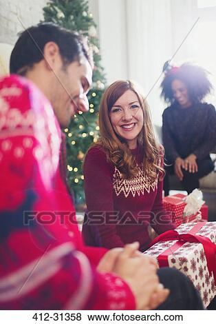 Portrait smiling woman opening Christmas gifts with friends View Large Photo Image Stock Photo - Portrait smiling woman opening Christmas gifts with friends. Fotosearch