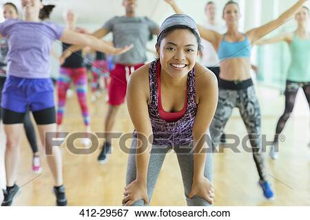 Stock Photo - Portrait smiling woman resting with hands on knees in exercise class. Fotosearch