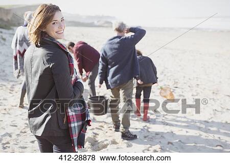 Portrait smiling woman walking on sunny beach with family View Large Photo Image Stock Photo - Portrait smiling woman walking on sunny beach with family. Fotosearch