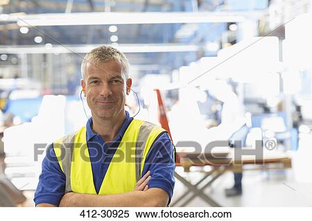 Stock Photography - Portrait smiling worker with earplugs in steel factory. Fotosearch