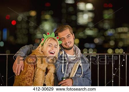 Portrait smiling young couple enjoying nighttime rooftop party View Large Photo Image Stock Photo - Portrait smiling young couple enjoying nighttime rooftop party. Fotosearch