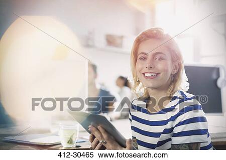 Stock Photography - Portrait smiling young creative businesswoman with digital tablet in office. Fotosearch