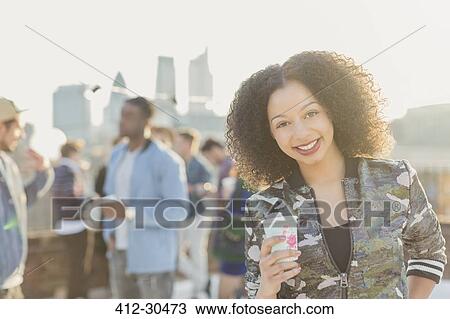 Portrait smiling young woman drinking cocktail at rooftop party View Large Photo Image Stock Image - Portrait smiling young woman drinking cocktail at rooftop party. Fotosearch