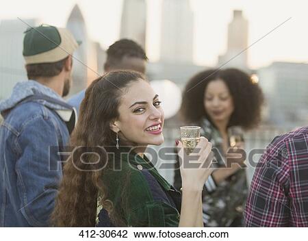 Portrait smiling young woman drinking champagne at rooftop party View Large Photo Image Stock Image - Portrait smiling young woman drinking champagne at rooftop party. Fotosearch