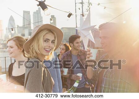 Portrait smiling young woman drinking beer at rooftop party View Large Photo Image Stock Photo - Portrait smiling young woman drinking beer at rooftop party. Fotosearch