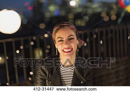 Stock Photo - Portrait smiling young woman enjoying rooftop party. Fotosearch