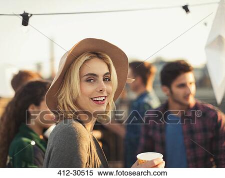 Stock Photography - Portrait smiling young woman enjoying rooftop party. Fotosearch