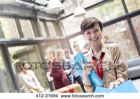 Portrait smiling young woman handing out packets at conference View Large Photo Image Picture - Portrait smiling young woman handing out packets at conference. Fotosearch