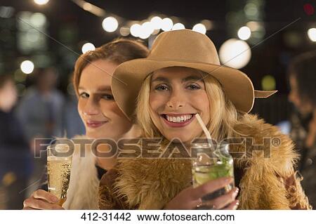 Portrait smiling young women drinking cocktails at party View Large Photo Image Stock Image - Portrait smiling young women drinking cocktails at party. Fotosearch
