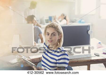 Stock Image - Portrait young adult businesswoman using digital tablet in office. Fotosearch