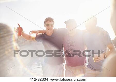 Portrait young men drinking beer at sunny poolside party View Large Photo Image Picture - Portrait young men drinking beer at sunny poolside party. Fotosearch