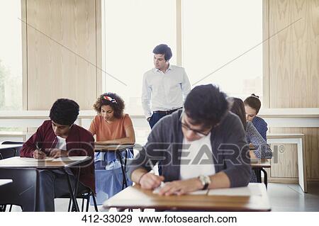 Professor watching college students taking test in classroom View Large Photo Image Stock Photo - Professor watching college students taking test in classroom. Fotosearch