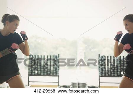 Stock Photo - Reflection of woman shadow boxing at gym studio mirror. Fotosearch