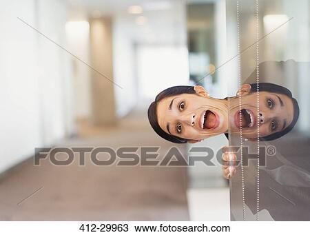 Reflection portrait of exuberant woman peering into office corridor View Large Photo Image Stock Image - Reflection portrait of exuberant woman peering into office corridor. Fotosearch