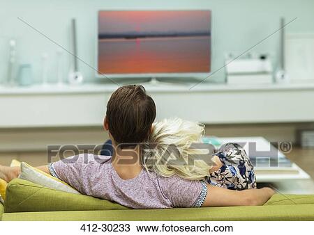 Relaxed couple watching TV on living room sofa View Large Photo Image Stock Image - Relaxed couple watching TV on living room sofa. Fotosearch