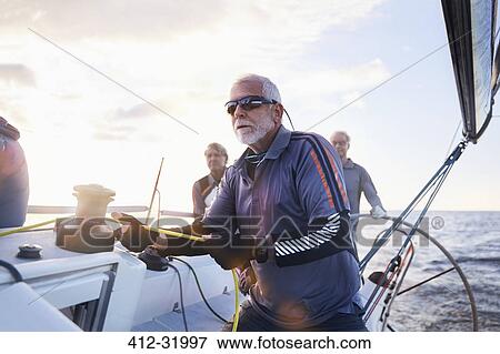 Stock Photo - Retired man sailing holding rigging on sailboat. Fotosearch