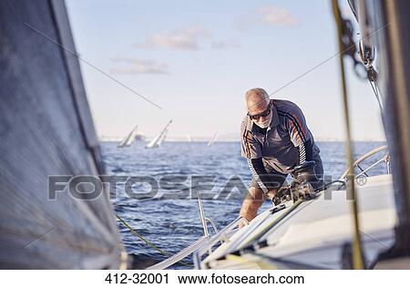 Stock Image - Retired man sailing sailboat. Fotosearch