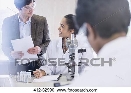 Stock Image - Science professor helping college student conducting scientific experiment in science laboratory classroom. Fotosearch