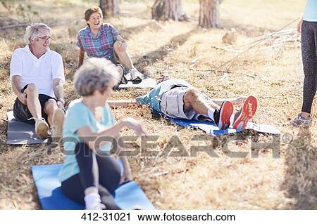 Stock Image - Senior adults practicing yoga in sunny park. Fotosearch