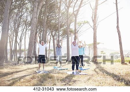 Stock Image - Senior adults practicing yoga in sunny park. Fotosearch