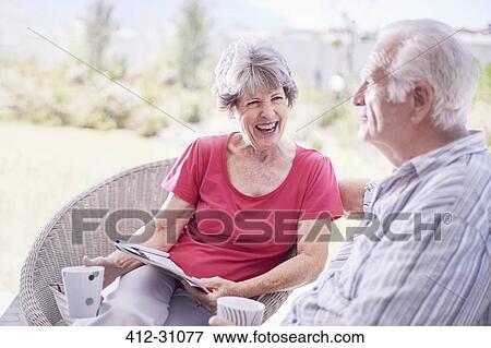 Senior couple drinking coffee and reading magazine on patio View Large Photo Image Stock Photo - Senior couple drinking coffee and reading magazine on patio. Fotosearch