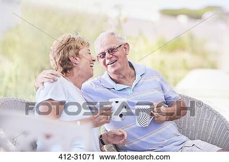 Stock Image - Senior couple hugging and drinking coffee on patio. Fotosearch