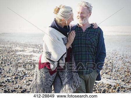 Senior couple hugging and walking on sunny rocky beach View Large Photo Image Stock Photo - Senior couple hugging and walking on sunny rocky beach. Fotosearch