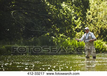 Stock Photo - Senior man fly fishing at summer river. Fotosearch