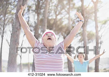 Senior woman stretching arms overhead in yoga class in sunny park View Large Photo Image Picture - Senior woman stretching arms overhead in yoga class in sunny park. Fotosearch