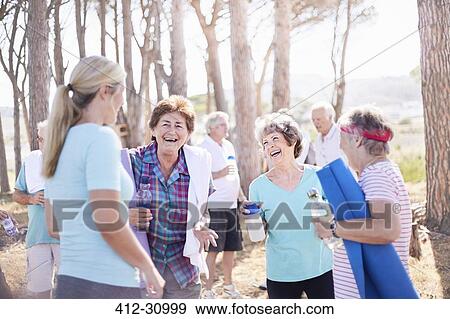 Stock Photo - Senior women talking after yoga class in park. Fotosearch