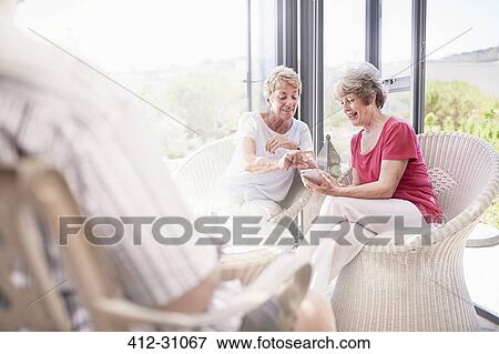 Stock Photo - Senior women using cell phone on patio. Fotosearch