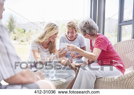 Stock Photograph - Senior women using cell phone on patio. Fotosearch