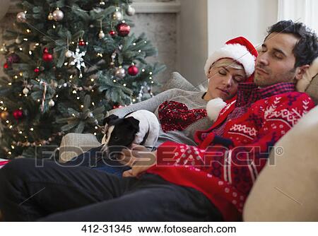 Serene couple napping with dog on sofa next to Christmas tree View Large Photo Image Stock Photography - Serene couple napping with dog on sofa next to Christmas tree. Fotosearch