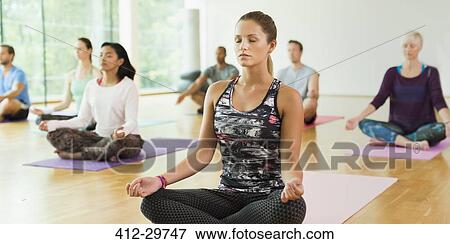 Stock Photo - Serene woman in lotus position with eyes closed in yoga class. Fotosearch