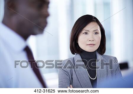 Stock Photography - Serious businesswoman listening in meeting. Fotosearch