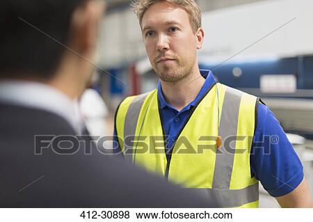Serious worker listening to manager in steel factory View Large Photo Image Stock Photo - Serious worker listening to manager in steel factory. Fotosearch