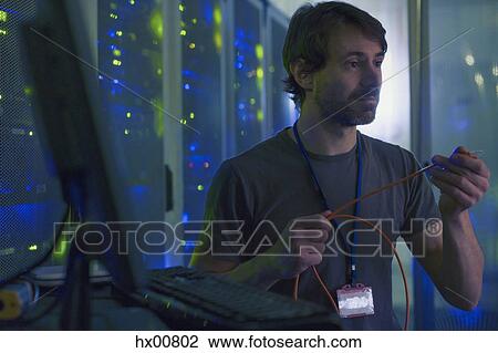 Server room technician examining cable at computer View Large Photo Image Stock Image - Server room technician examining cable at computer. Fotosearch
